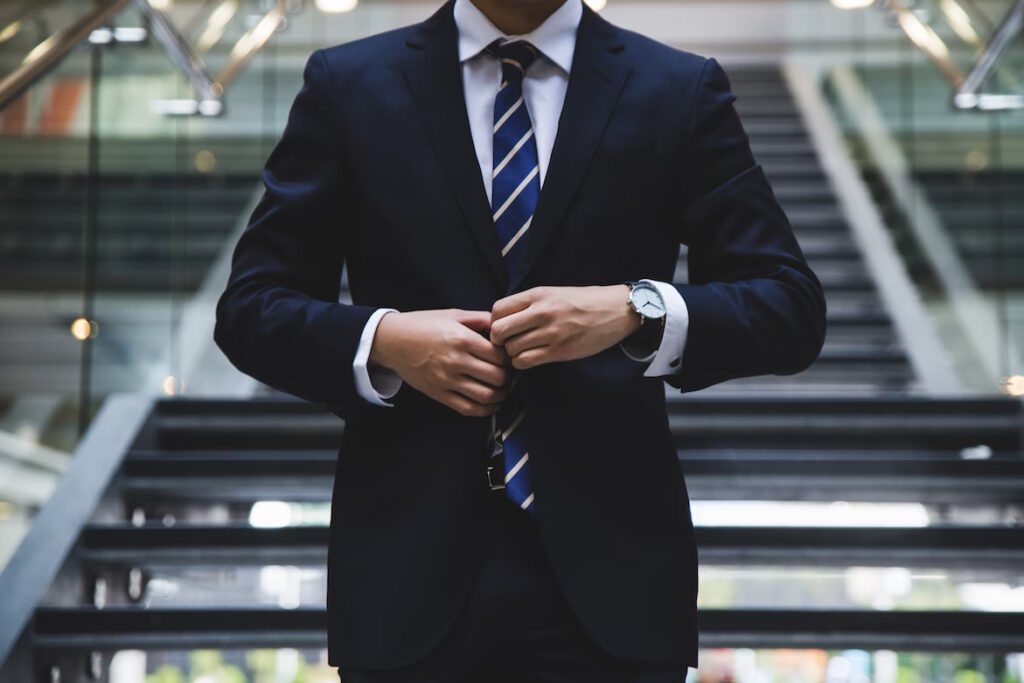 a man in a suit fixing his tie against the stairs