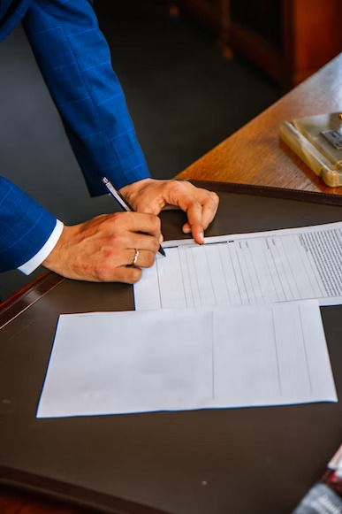 a man in blue coat writing something on a paper