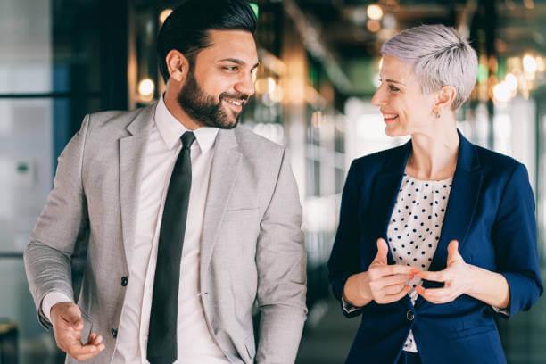 a man and a woman talking to each other while smiling