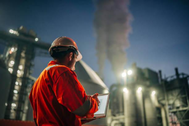 a person in orange jacket and hardhat using a laptop