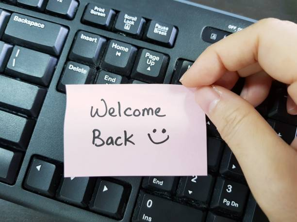 a hand holding a "welcome back" note with a smiley face