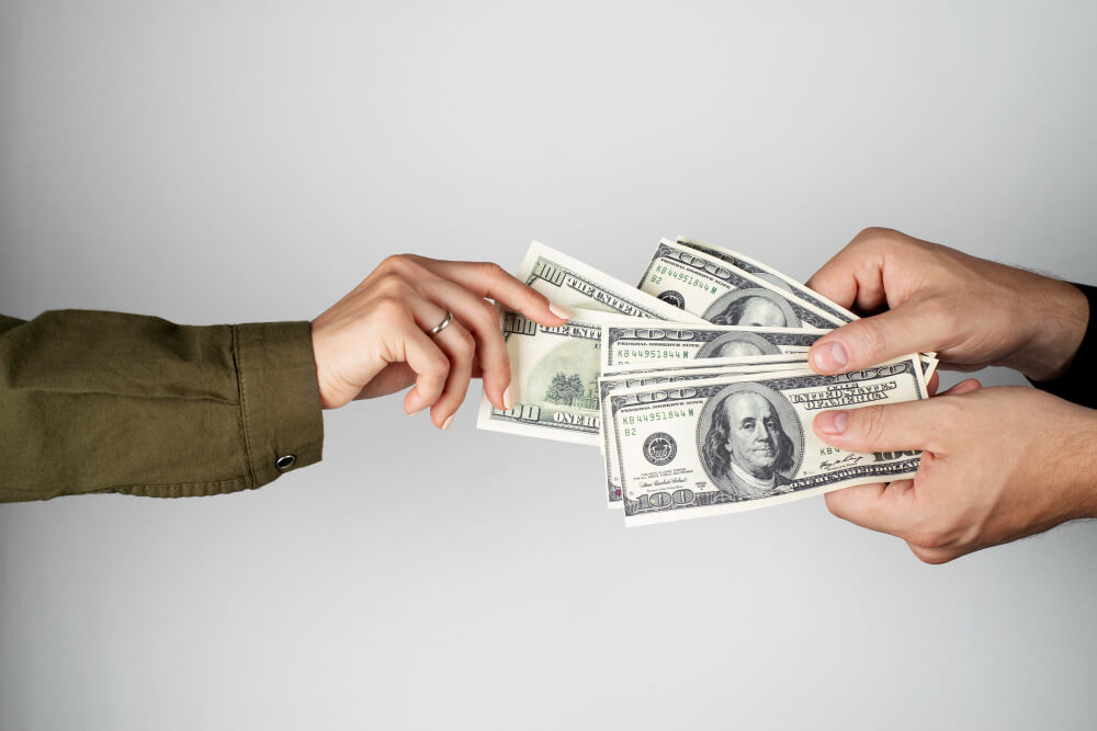 a hand reaching for some money from another pair of hands