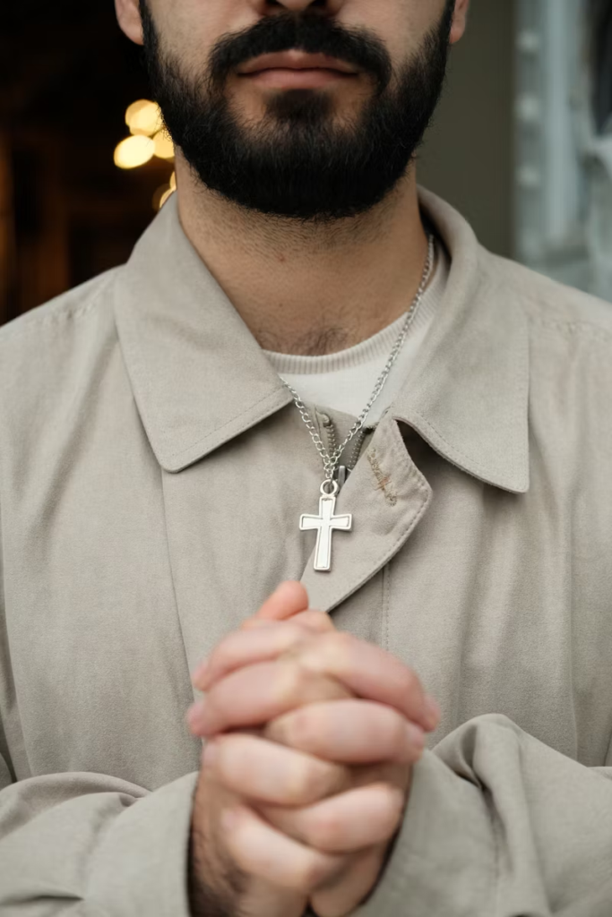 a man praying, wearing a cross necklace